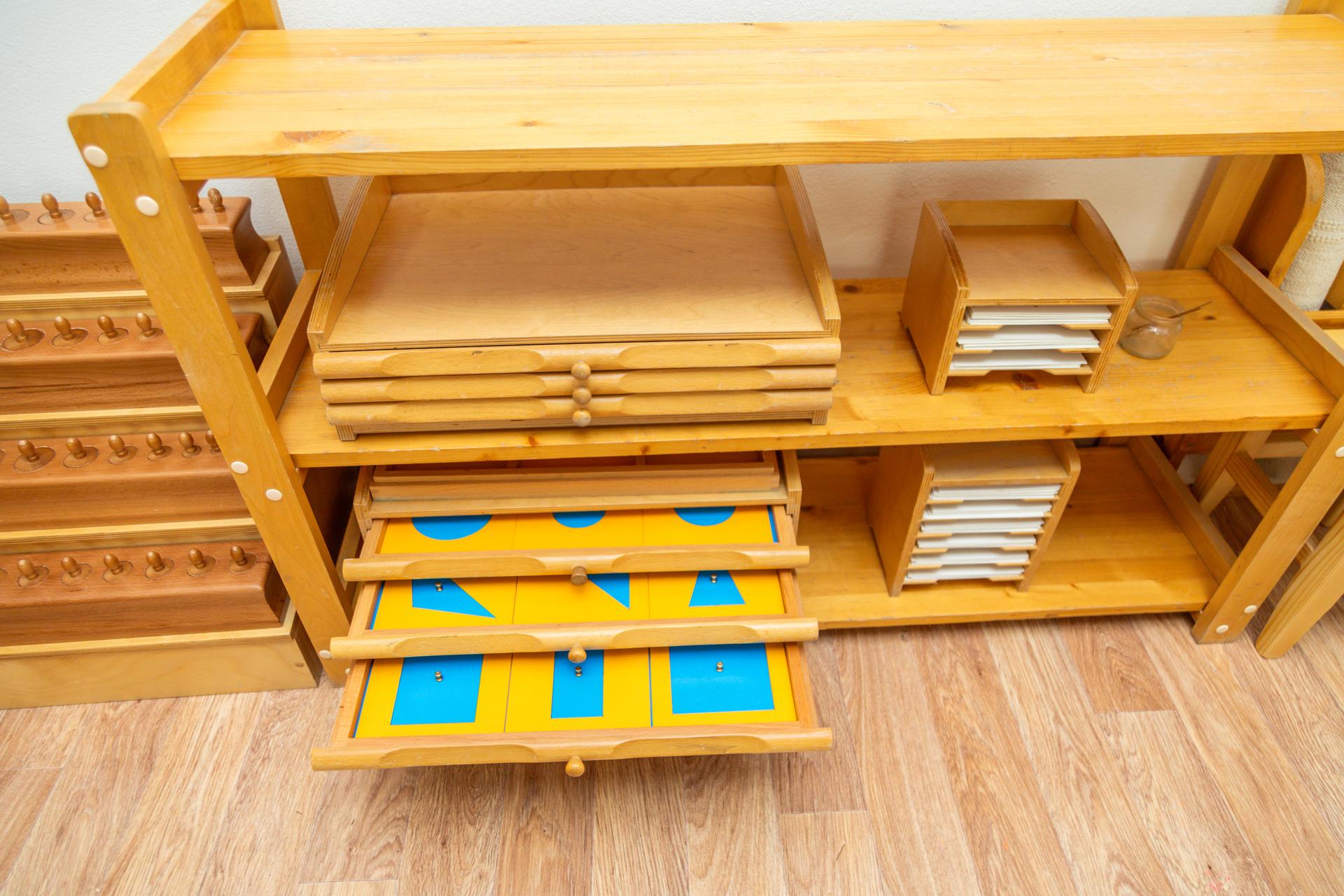 Montessori shelf with wooden educational materials and drawers